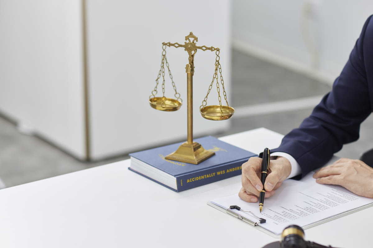 공증 사무소 책상에서 담당자가 펜으로 서류에 서명하며 위임장 사실공증 절차를 진행하는 모습