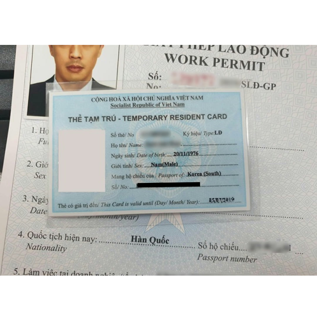 베트남에서 발급된 노동허가서 양식 위에 임시 거주증 카드가 놓여 있고, 국적과 유효 기간 항목이 보입니다.